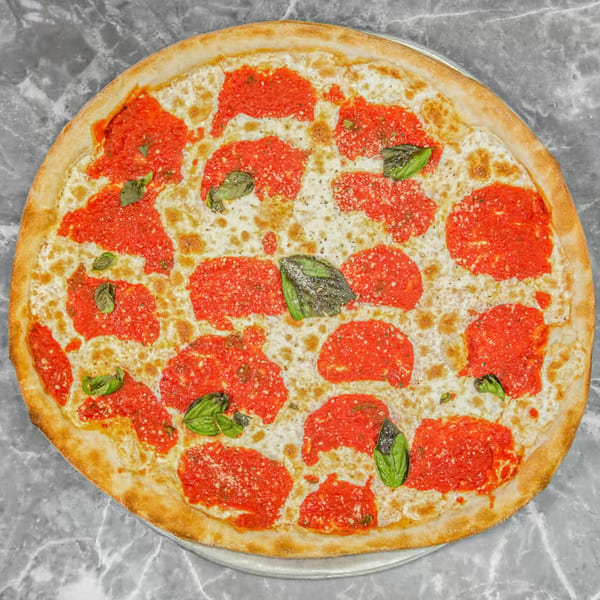 Pino's La Forchetta pizza with red sauce, melted mozzarella, and fresh basil leaves on a marble surface.