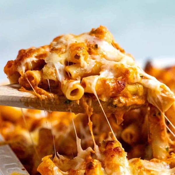 Cheesy baked ziti with marinara sauce being served with a wooden spoon, cheese stretching.