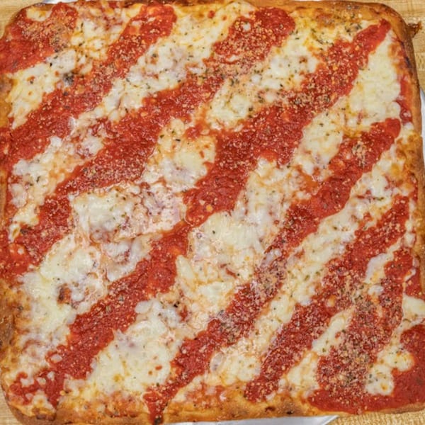 Square Sicilian pizza from Pino's La Forchetta with diagonal stripes of red sauce and melted mozzarella cheese.